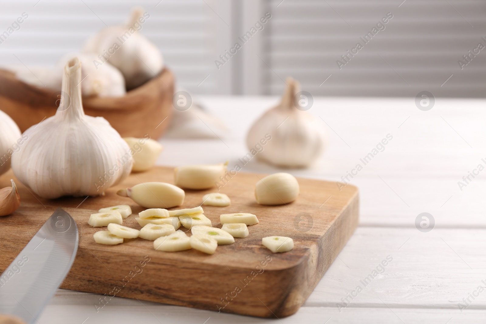 Photo of Aromatic cut garlic, cloves and bulbs on white wooden table, closeup. Space for text
