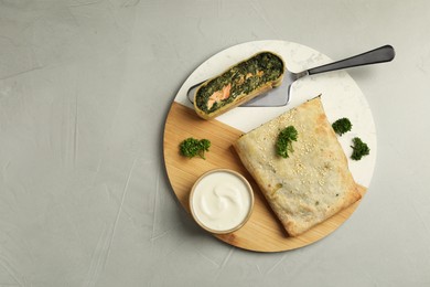 Photo of Delicious strudel with salmon and spinach served on light grey table, top view. Space for text