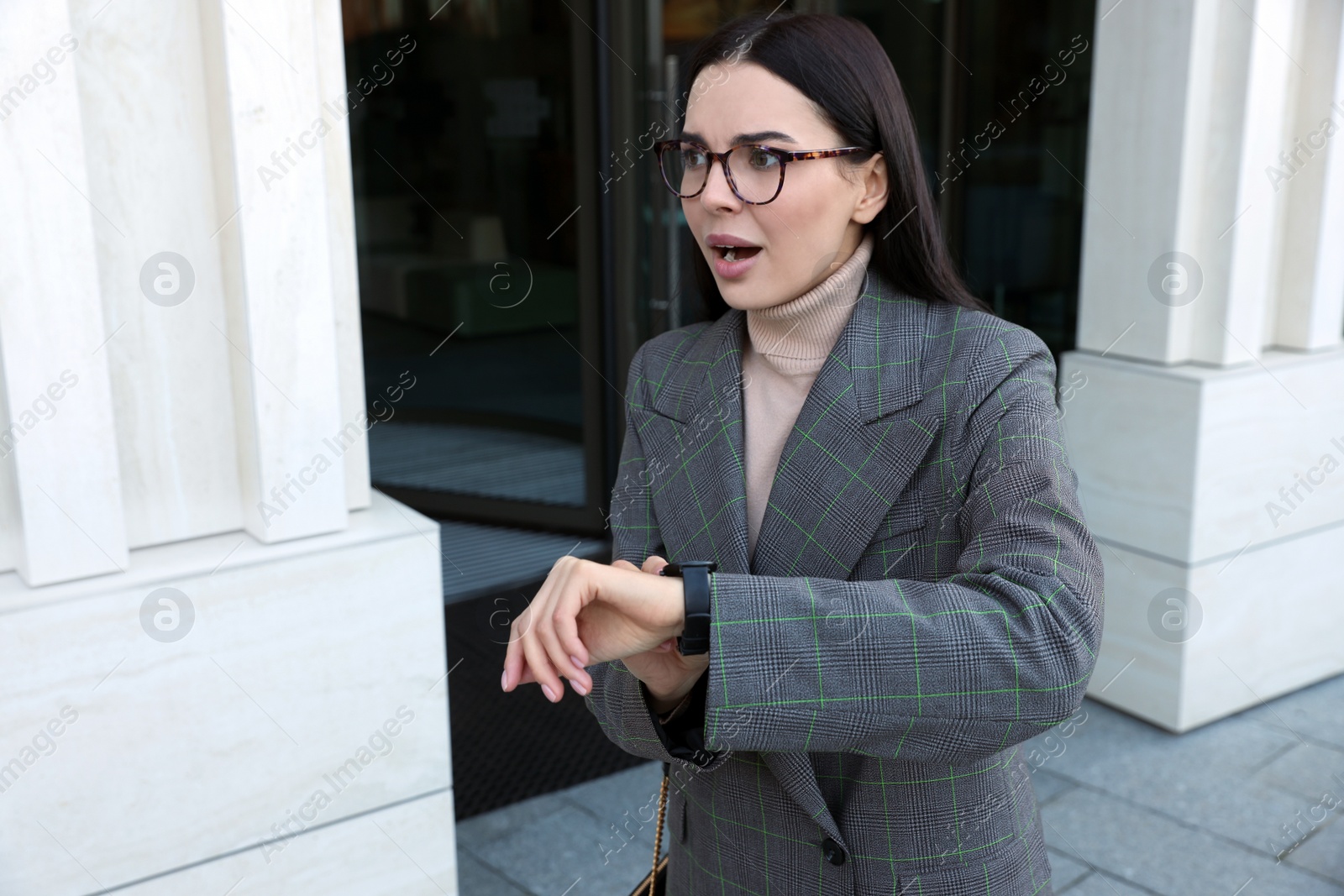 Photo of Emotional woman checking time on watch outdoors. Being late concept