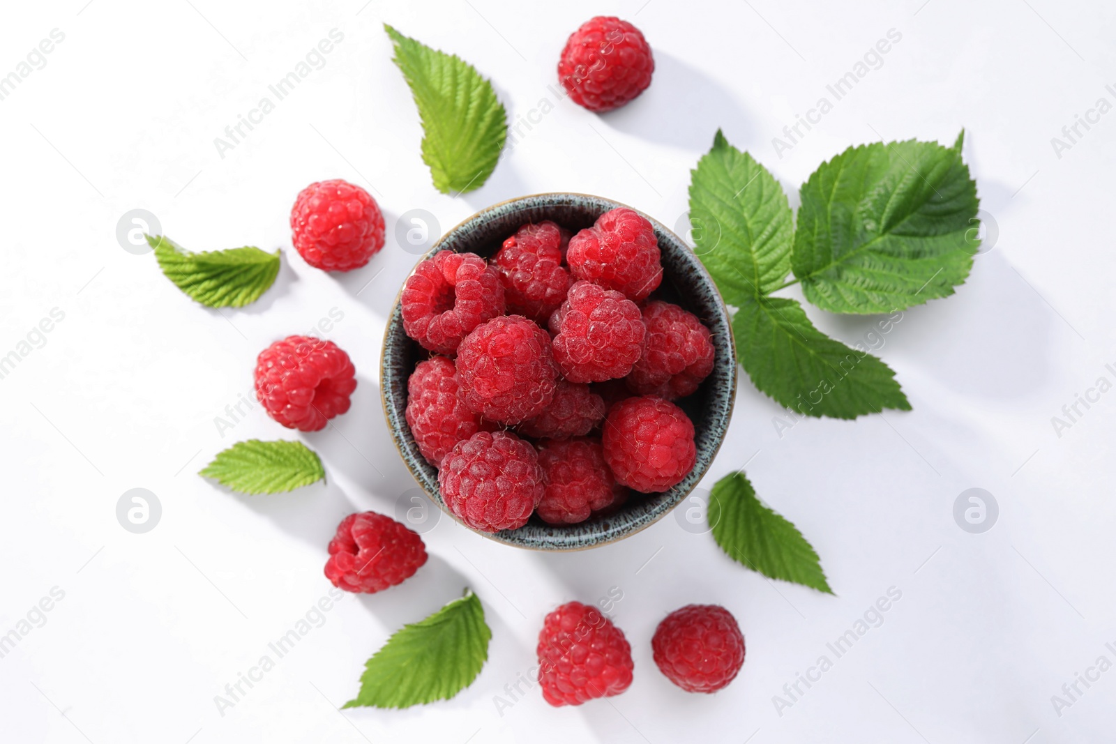 Photo of Tasty ripe raspberries and green leaves on white background, flat lay