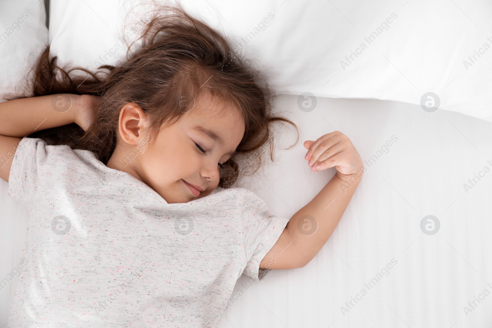 Photo of Cute little girl sleeping on cozy bed, view from above