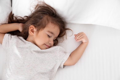 Cute little girl sleeping on cozy bed, view from above