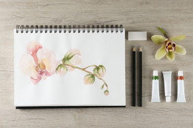 Flat lay composition with beautiful drawing of orchid
flowers on wooden table