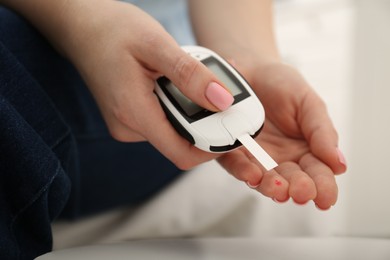 Photo of Diabetes. Woman checking blood sugar level with glucometer at home, closeup