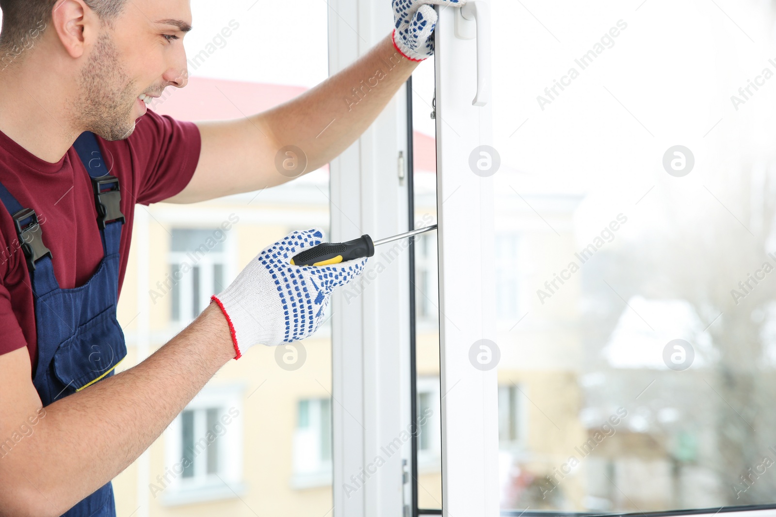 Photo of Construction worker adjusting installed window with screwdriver indoors