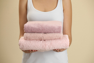 Woman holding fresh towels on beige background, closeup