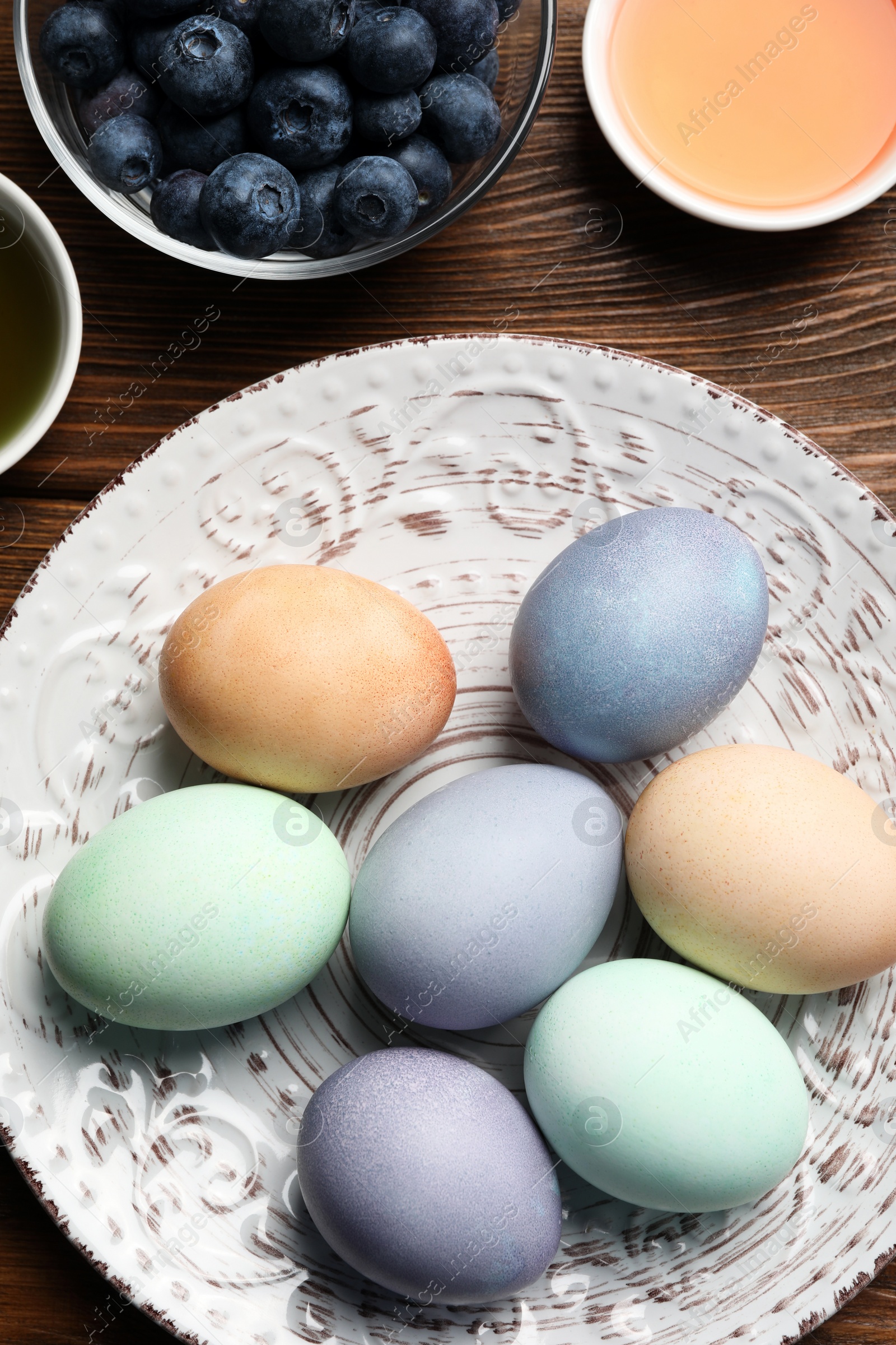 Photo of Naturally painted Easter eggs on wooden table, flat lay. Blueberries and onion used for coloring