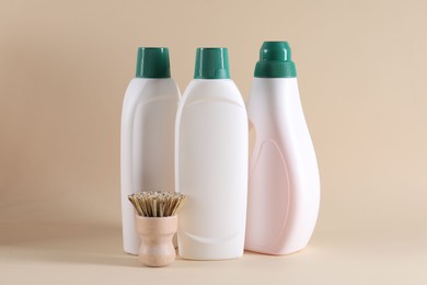 Bottles of cleaning product and brush on beige background