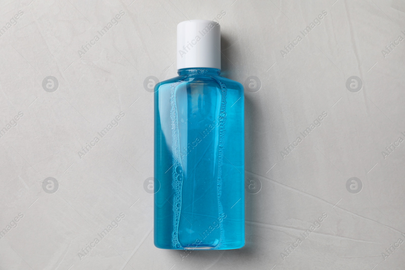 Photo of Fresh mouthwash in bottle on grey textured background, top view