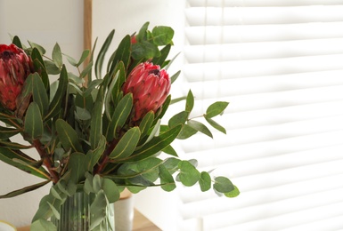 Photo of Vase with bouquet of beautiful Protea flowers indoors, closeup