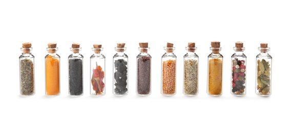 Row of small glass bottles with different spices on white background