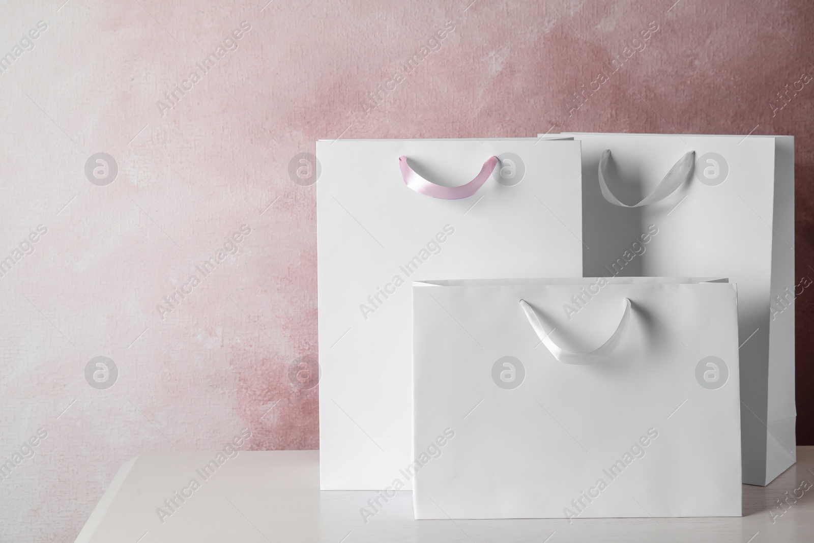 Photo of Paper shopping bags on table against color background. Mock up for design