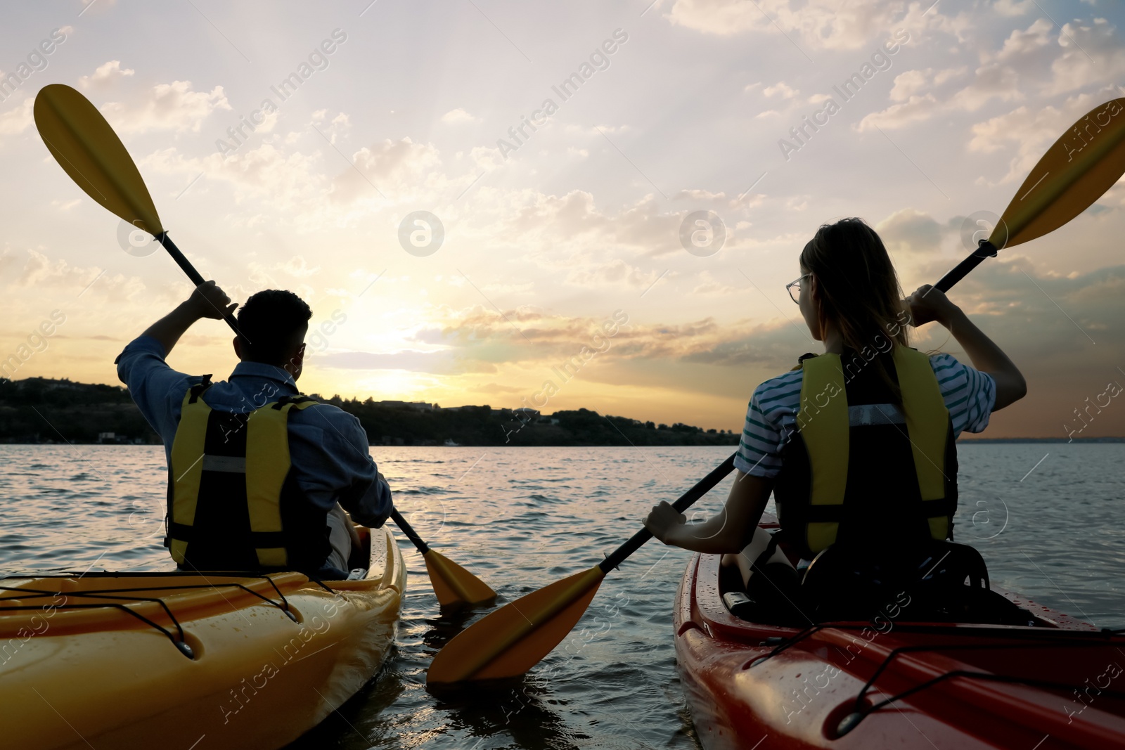 Photo of Couple in life jackets kayaking on river, back view. Summer activity