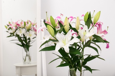 Photo of Vase with bouquet of beautiful lilies near mirror