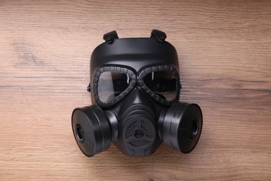 One gas mask on wooden background, top view