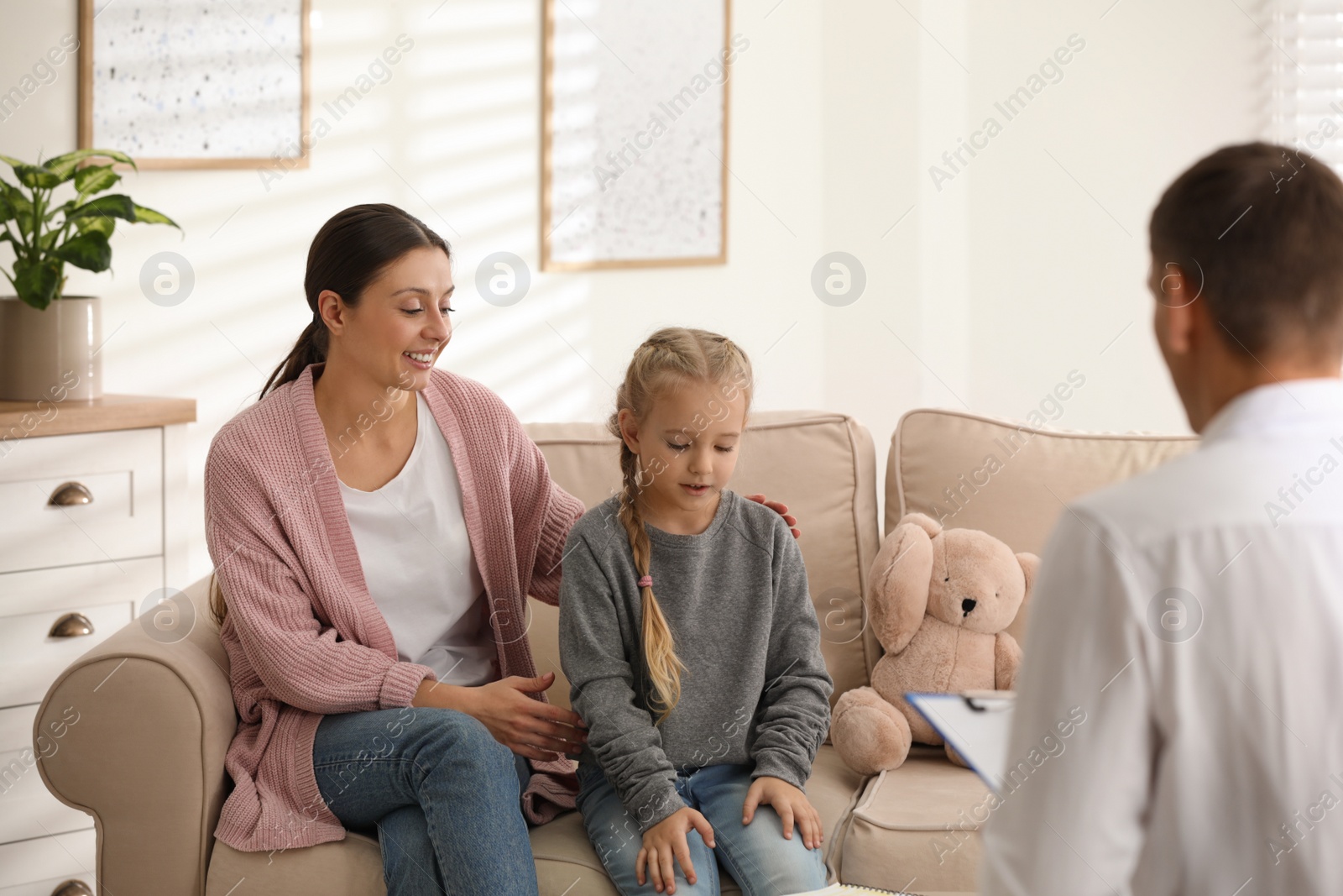 Photo of Child psychotherapist working with little girl and her mother in office