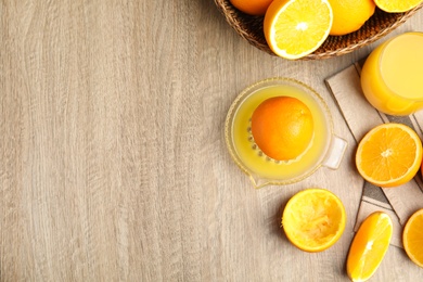 Photo of Squeezer, fresh oranges and juice on wooden table, flat lay. Space for text