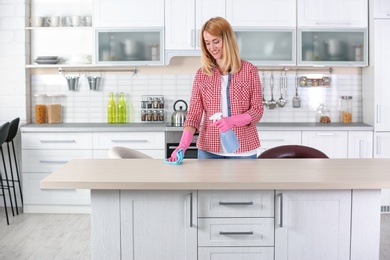 Photo of Woman cleaning table with rag in kitchen