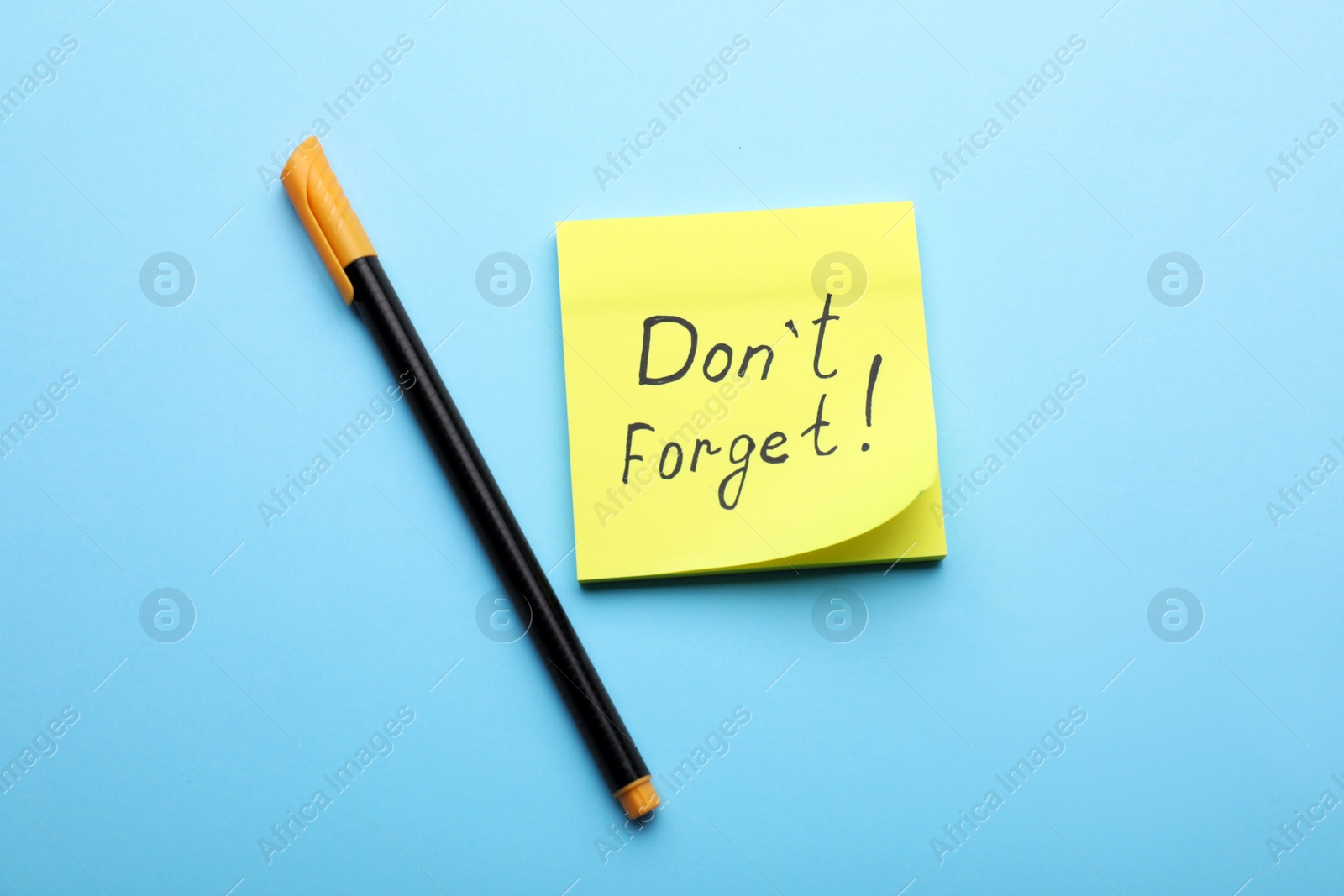 Photo of Paper note with phrase Don't Forget and pen on light blue background, flat lay