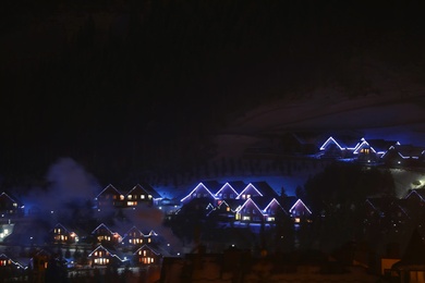 Night landscape with mountain village near forest in winter