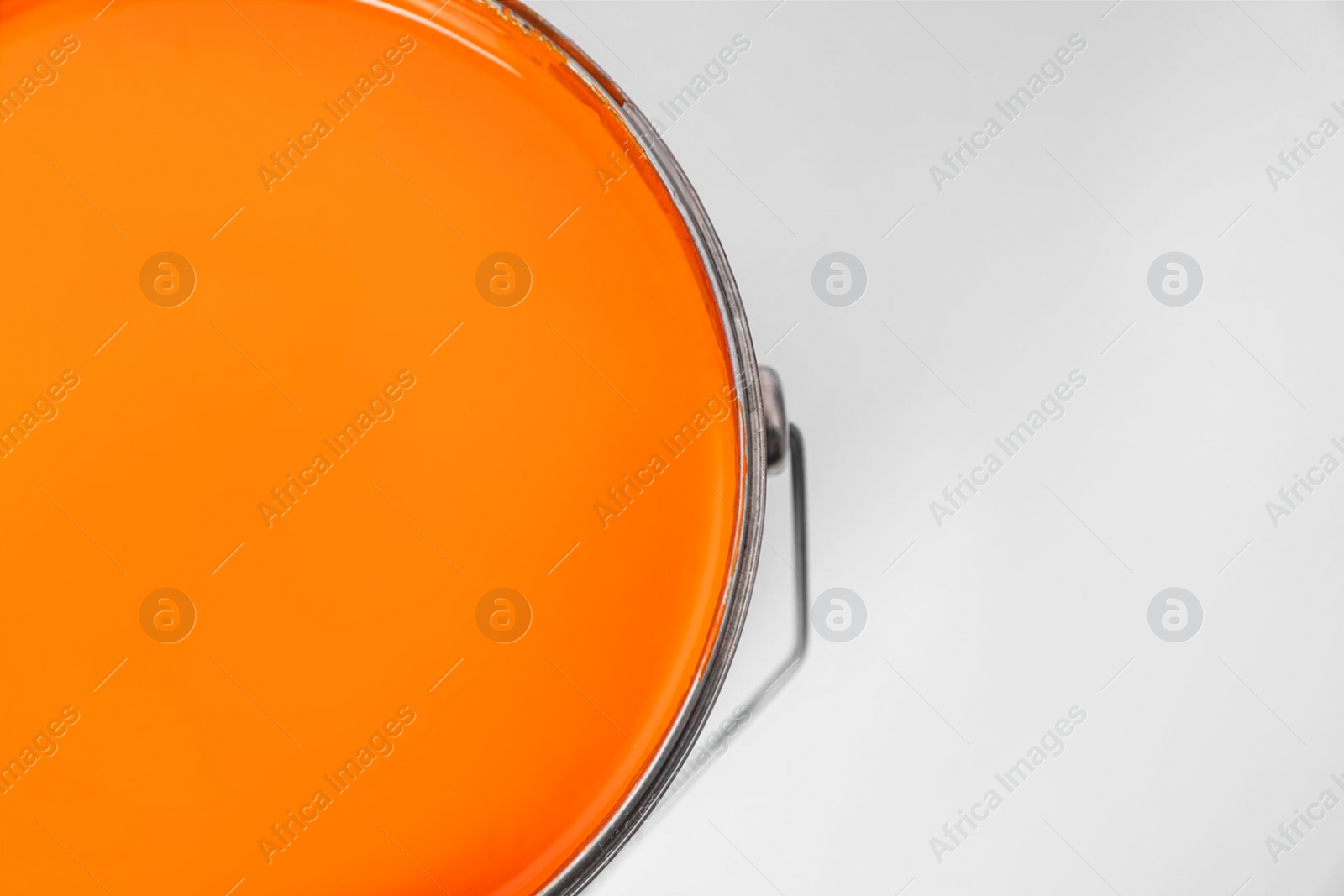 Photo of Bucket with orange paint on white background, top view. Space for text