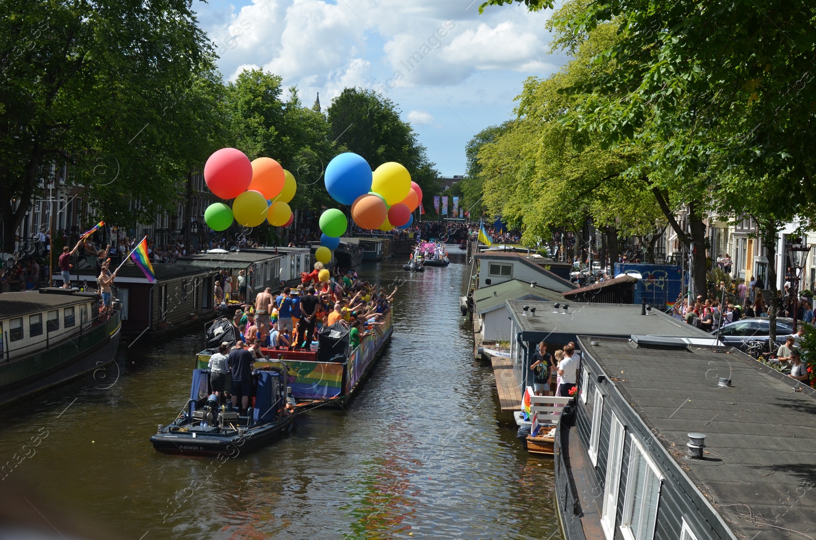 Photo of AMSTERDAM, NETHERLANDS - AUGUST 06, 2022: Many people in boats at LGBT pride parade on river