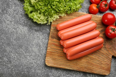 Photo of Fresh raw vegetarian sausages, lettuce and tomatoes on grey table, flat lay. Space for text