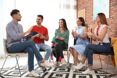 Group of young people learning sign language with teacher indoors