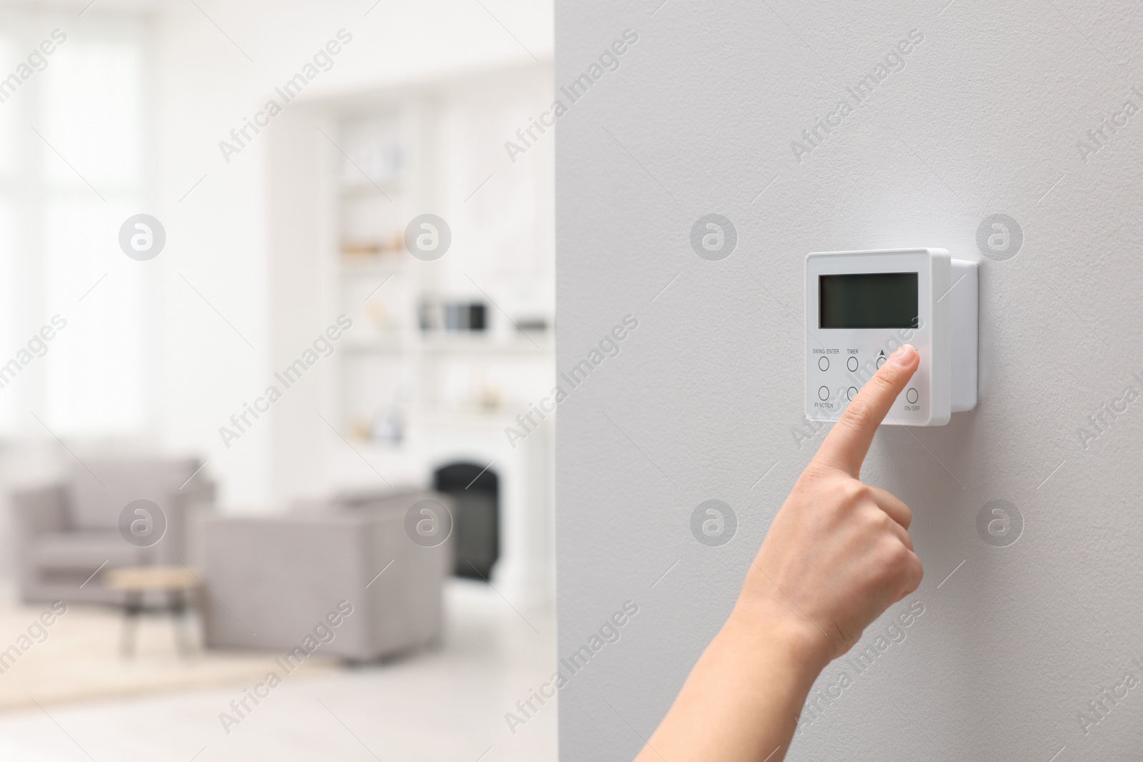 Photo of Woman adjusting thermostat on white wall indoors, closeup and space for text. Smart home system