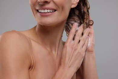 Happy woman washing hair on light grey background, closeup