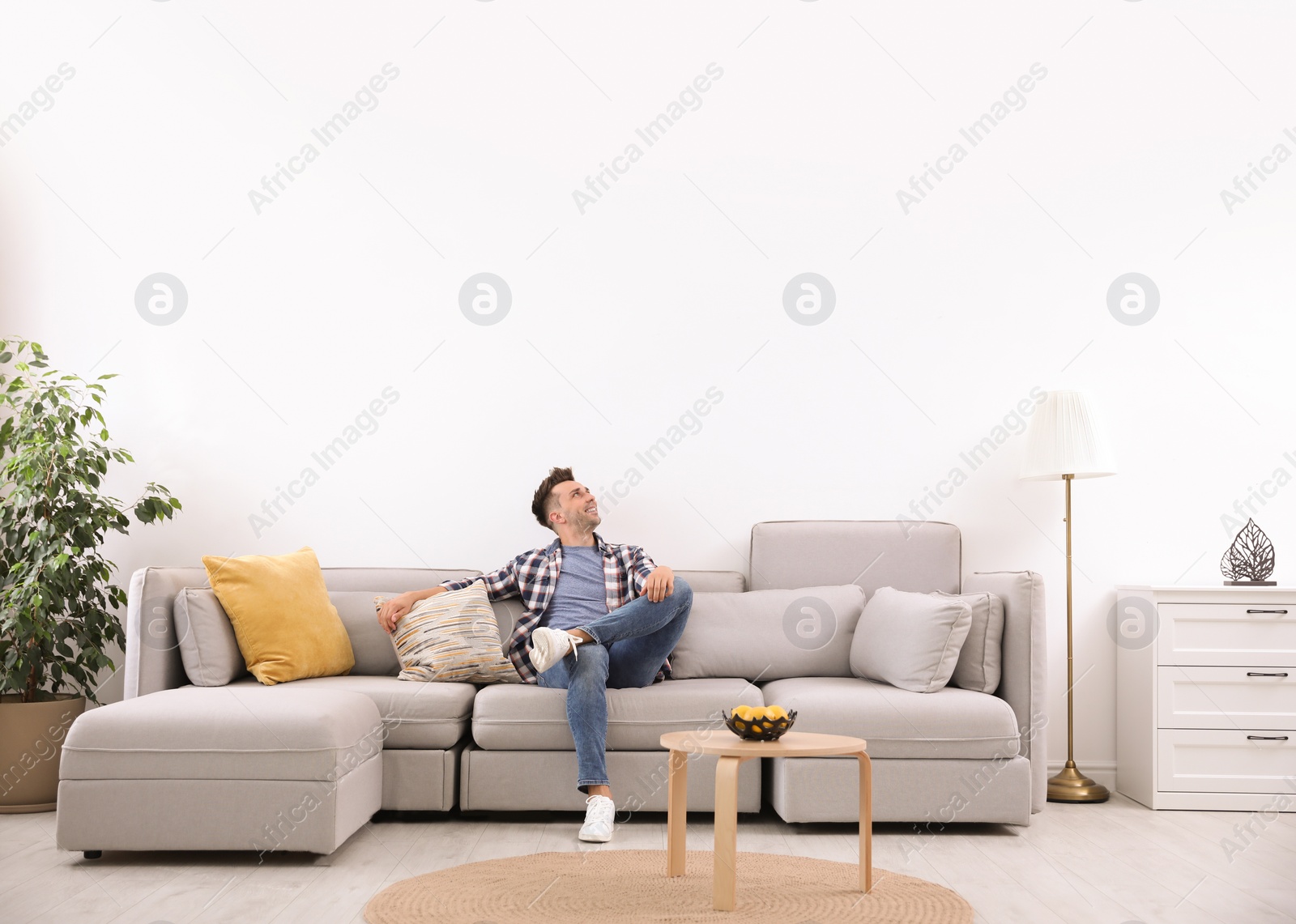 Photo of Young man relaxing on sofa under air conditioner at home