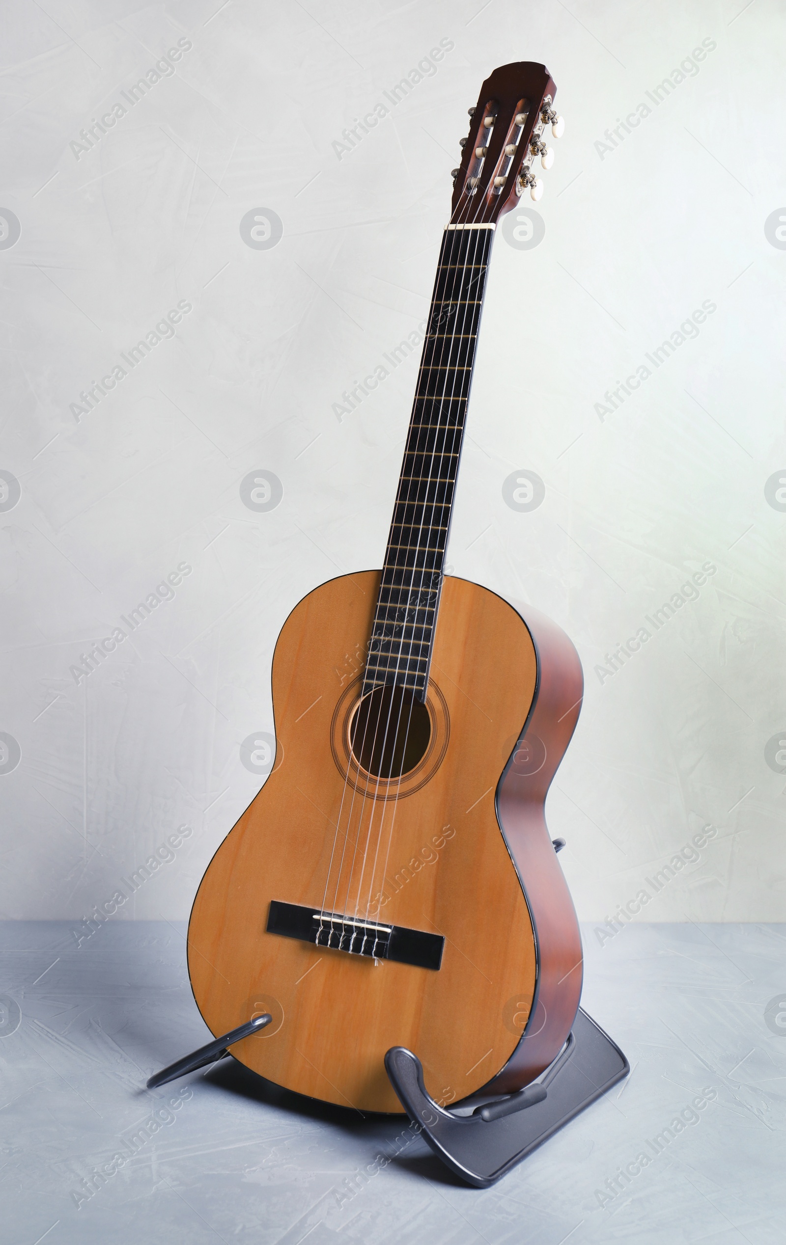 Photo of Beautiful classical guitar on stand near color wall