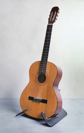 Beautiful classical guitar on stand near color wall