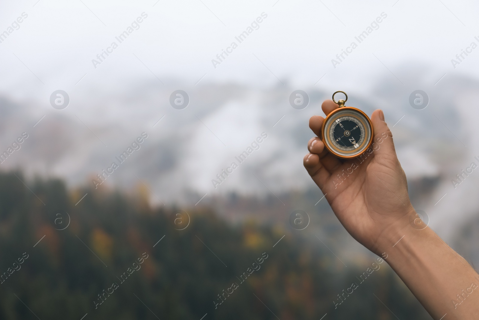 Photo of Woman using compass during journey in mountains, closeup. Space for text