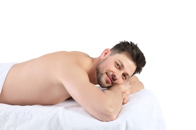 Photo of Handsome man relaxing on massage table against white background. Spa service