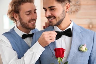 Happy newlywed gay couple with flower at home