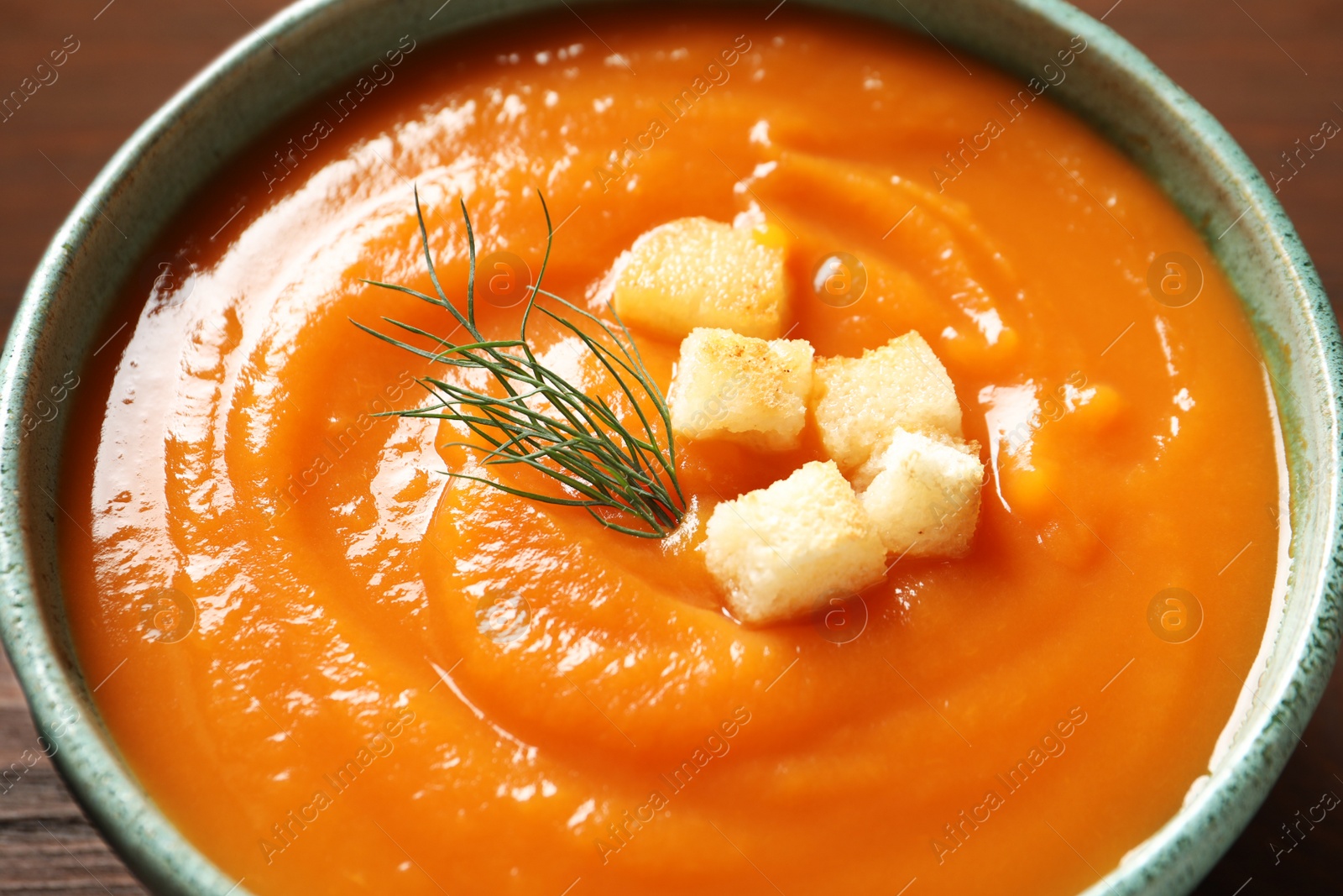 Photo of Bowl of tasty sweet potato soup served with croutons, closeup