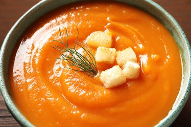 Bowl of tasty sweet potato soup served with croutons, closeup