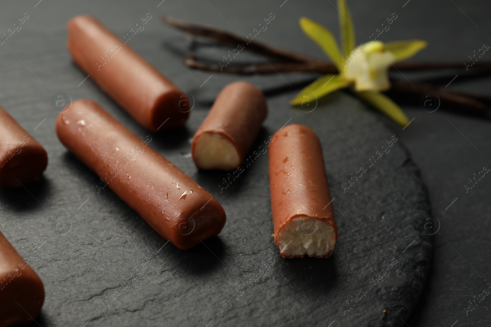 Photo of Glazed vanilla curd cheese bars on black table, closeup