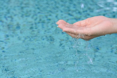 Photo of Water pouring into girl's hand above pool, closeup. Space for text