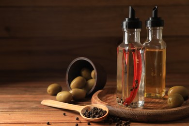 Photo of Different cooking oils and ingredients on wooden table. Space for text