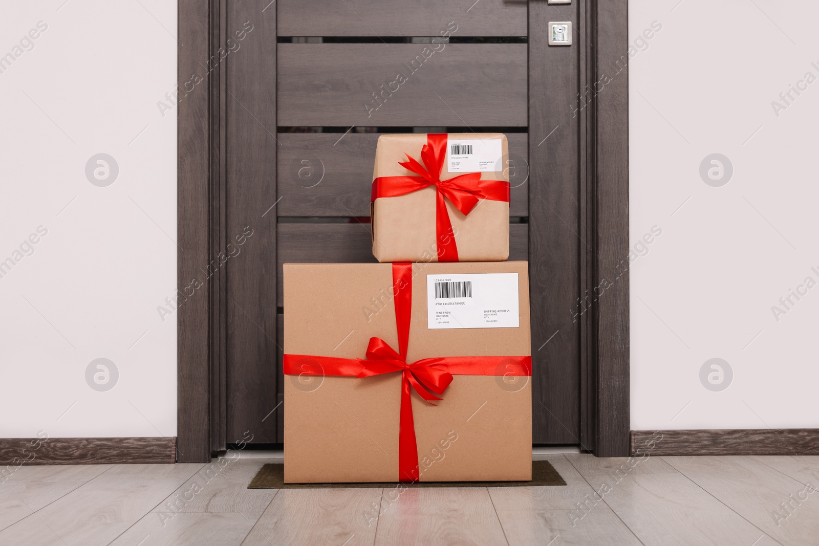 Photo of Christmas gift boxes on floor near door. Sending present by mail