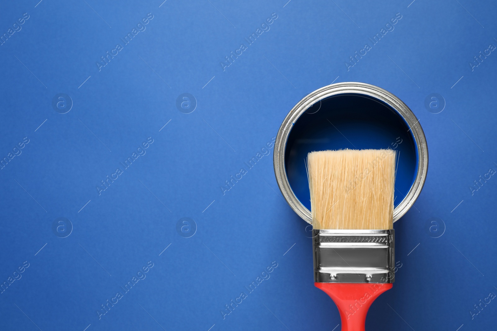 Photo of Can of paint and brush on bright background, top view with space for text. Color of the year 2020 (Classic blue)