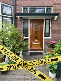 Yellow crime scene tape blocking way to house outdoors