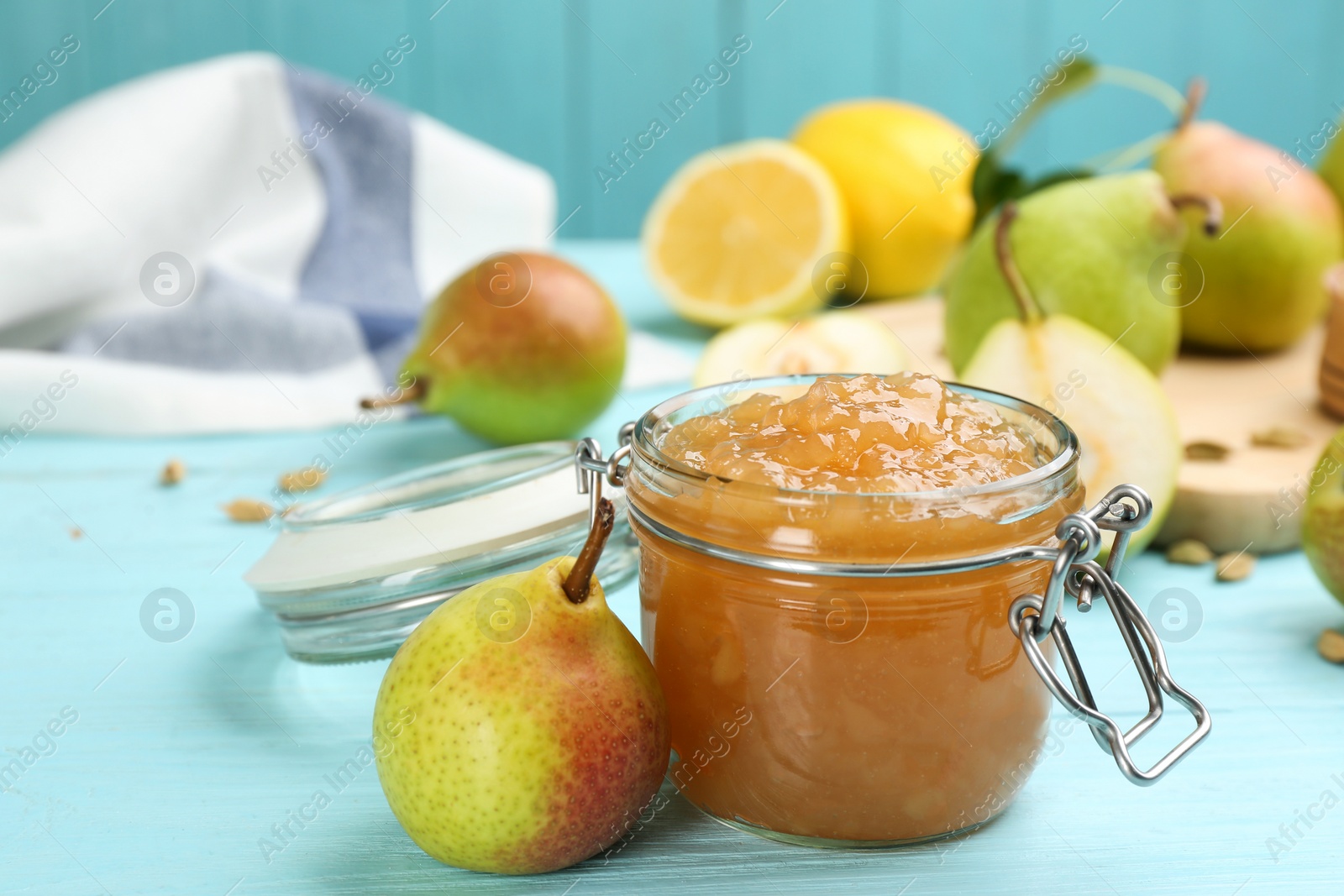 Photo of Tasty homemade pear jam and fresh fruits on light blue wooden table