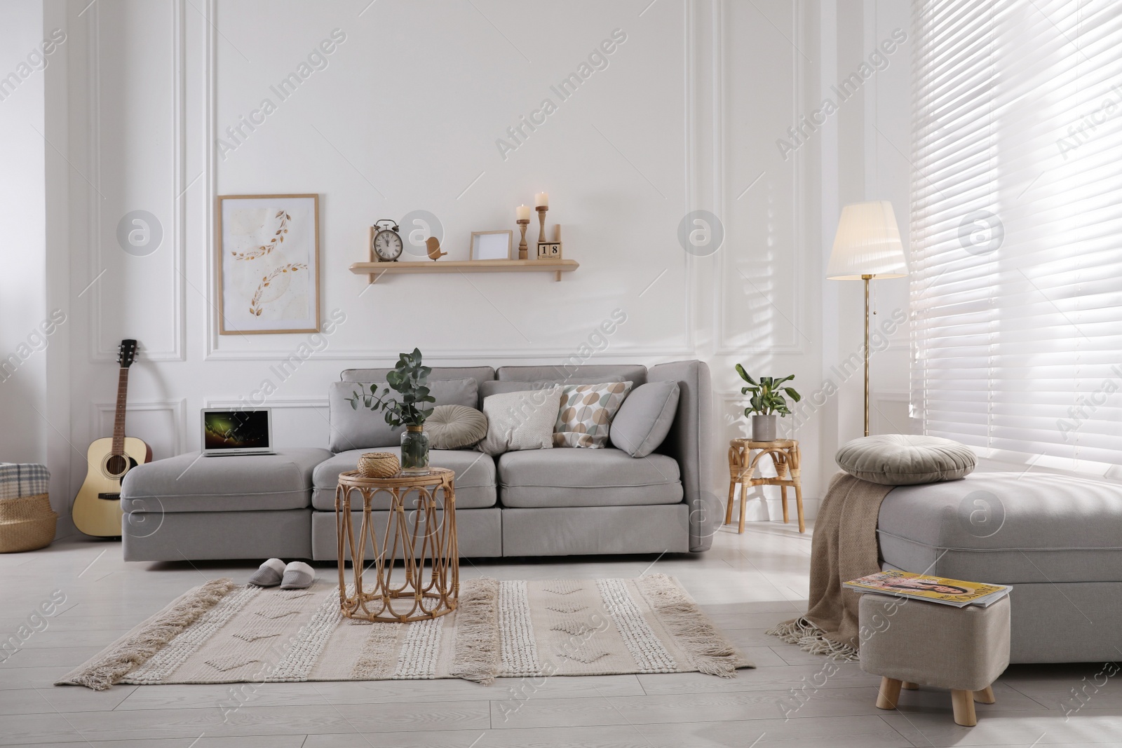 Photo of Living room with comfortable grey sofa, ottoman and stylish interior elements near window