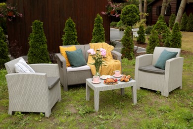 Breakfast served outdoors. Morning drink, food and vase with flowers on rattan table