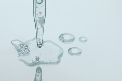 Glass pipette and transparent liquid on light background, closeup. Space for text