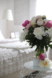 Photo of Beautiful blooming peonies on table in bedroom