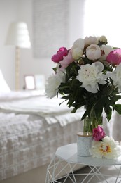 Beautiful blooming peonies on table in bedroom